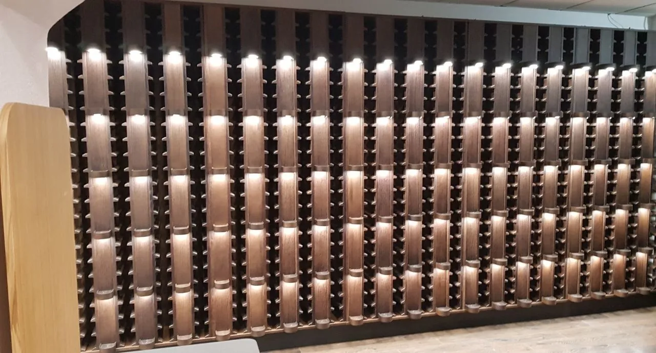 Wall of dark-stained bottle cradles with built-in lights in a wine boutique in Riga