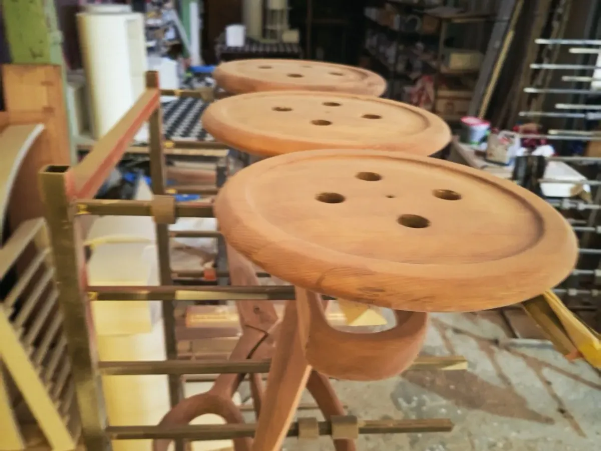 A small series of button-shaped wooden seats on a drying rack on the White Nordic floor