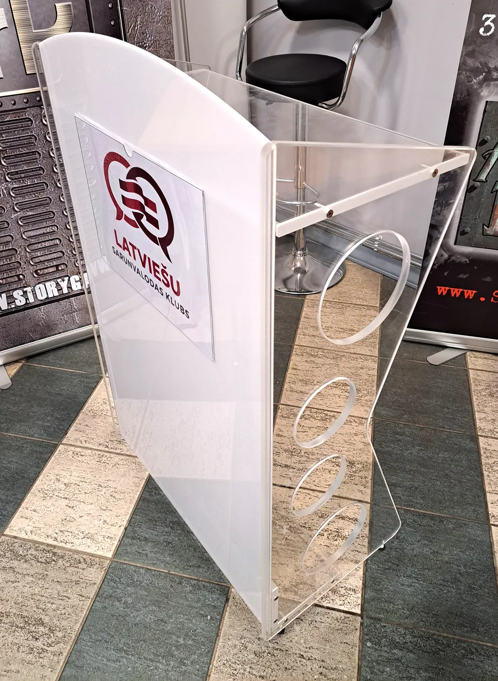 Lectern with a frosted white front carrying a club logo, and clear sides with round cut-outs
