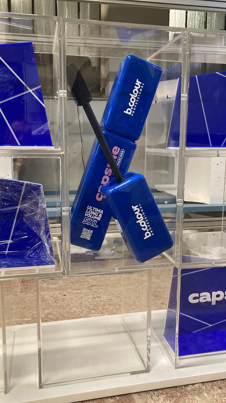 Large blue mascara model with its brush, inside a clear acrylic display case