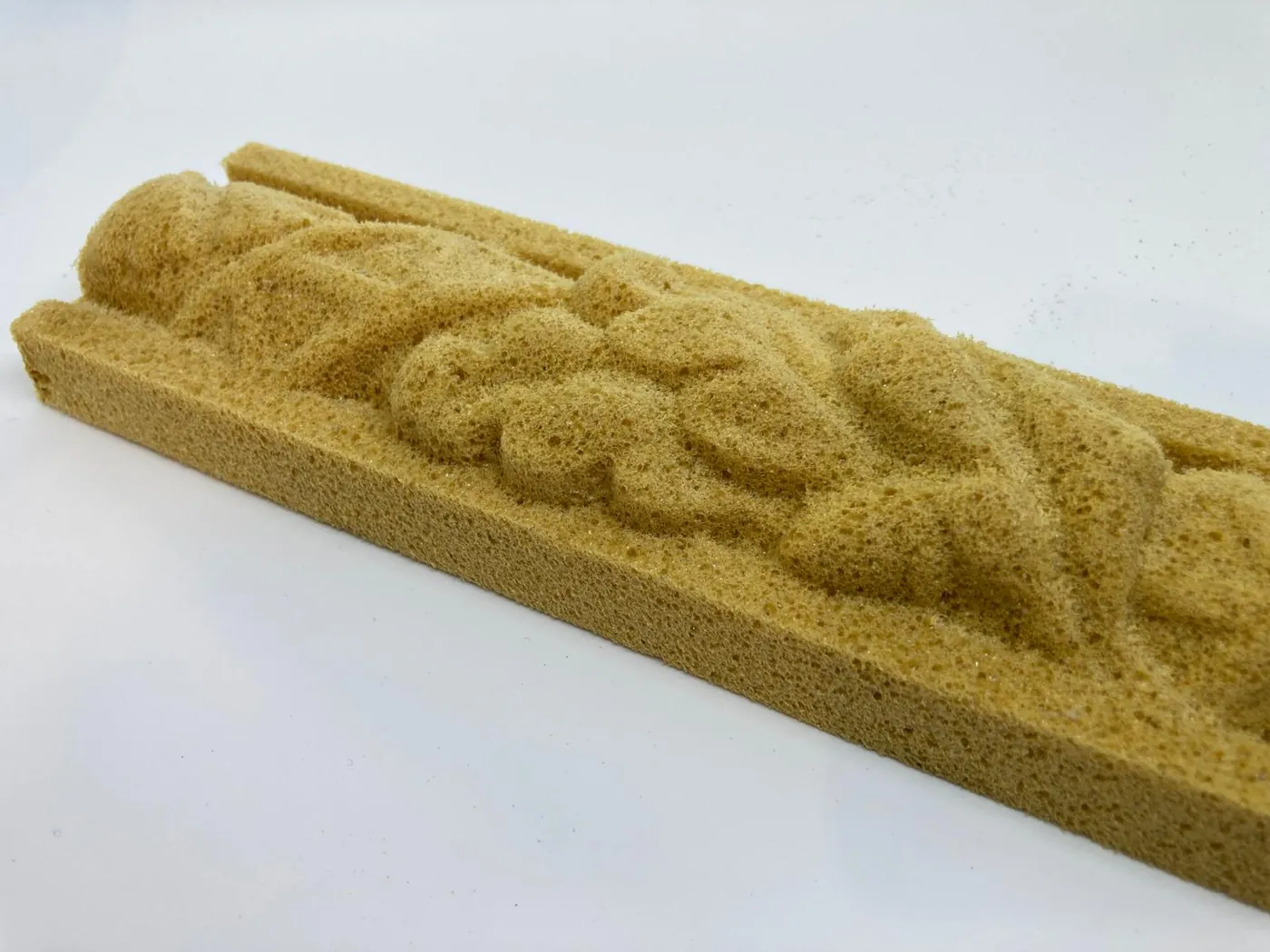 Yellow foam strip carved with a leaf ornament in relief