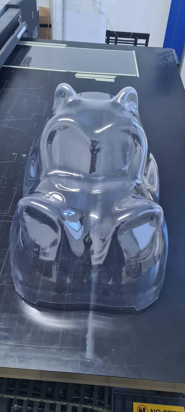 Clear plastic shell in the shape of an animal's head, lying on the machine bed