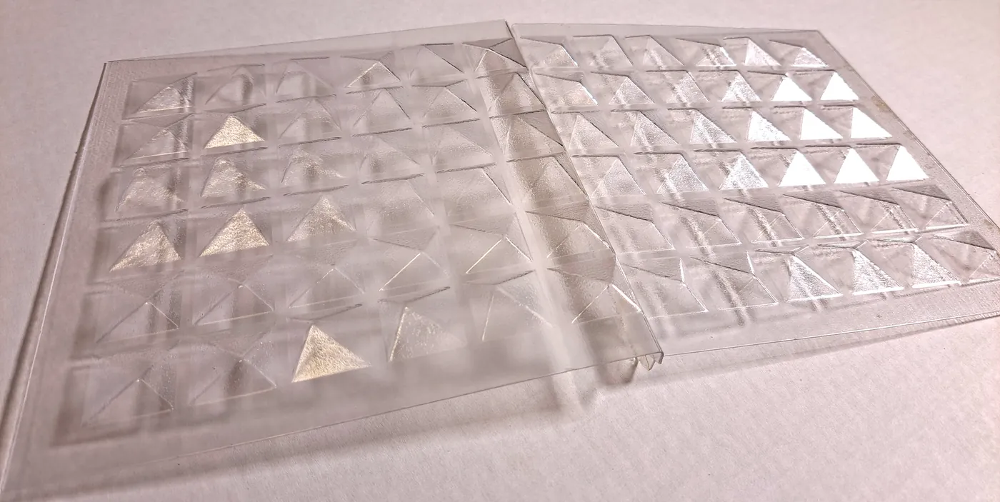 Two clear plastic sheets side by side, each formed with rows of small pyramids