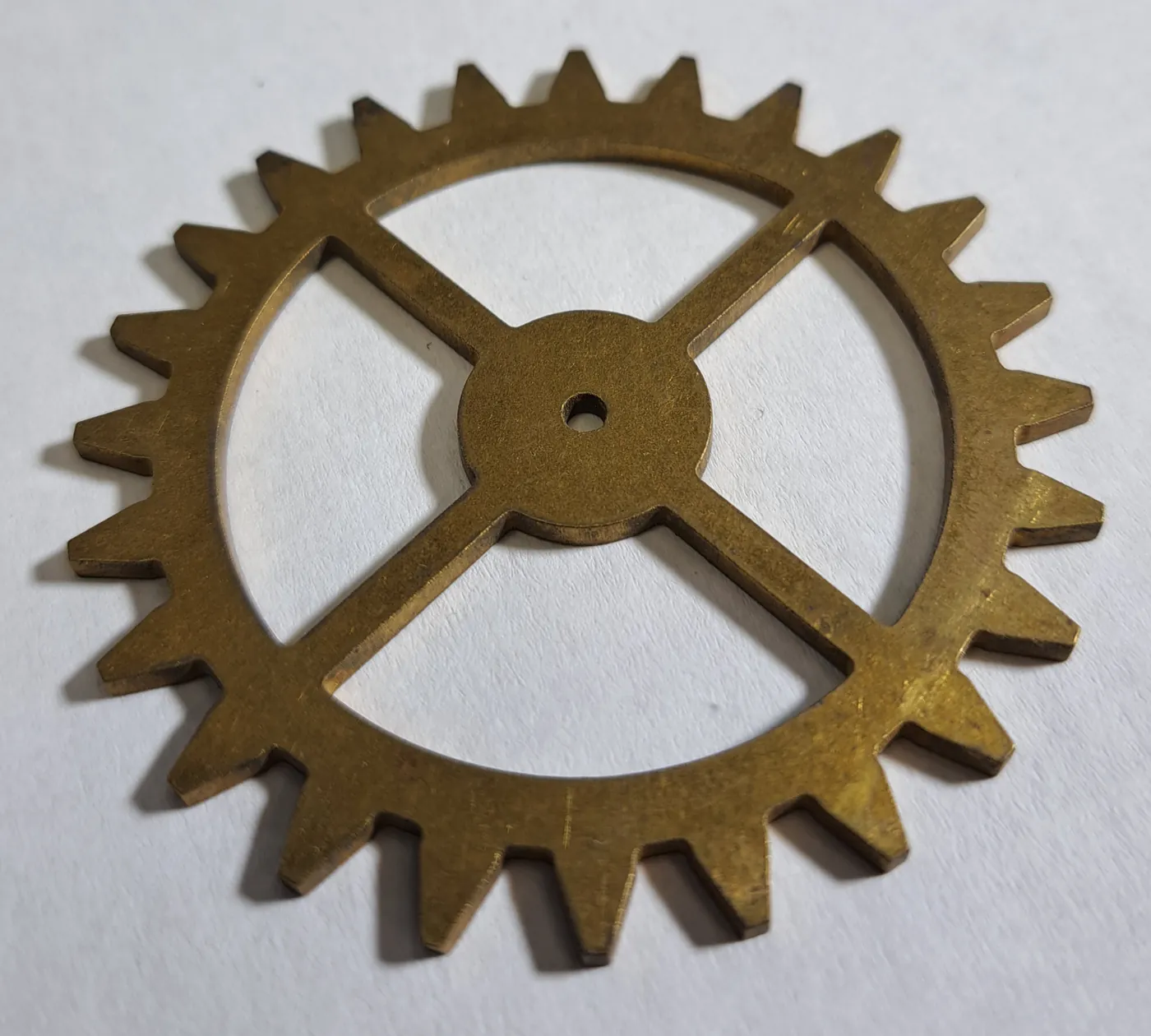 Gear wheel with four spokes, cut from gold-tone metal