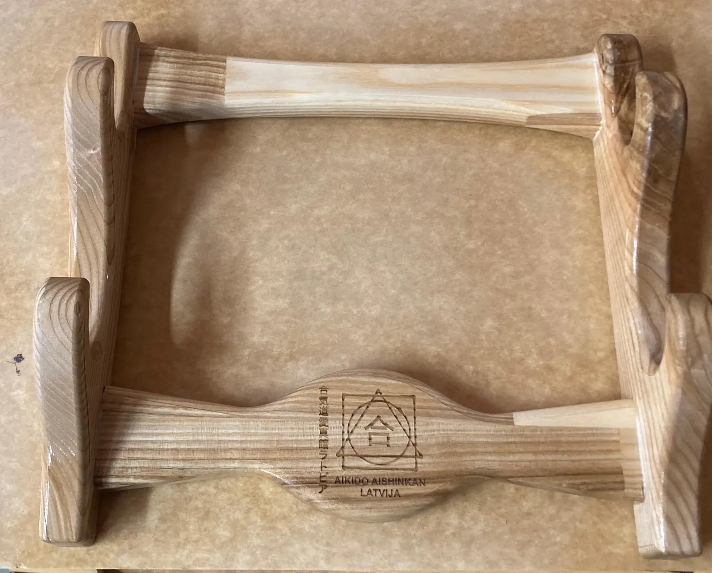 Wooden stand for training weapons, with shaped holders and an engraved club emblem on the crossbar