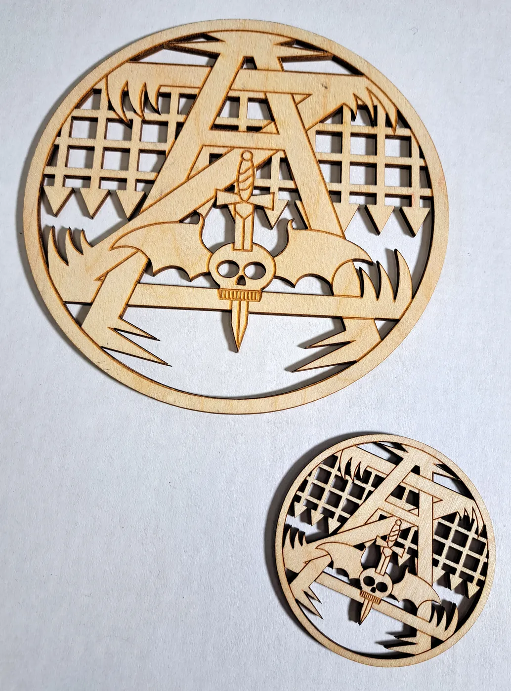 Large round plywood emblem in fretwork, with a matching smaller coaster