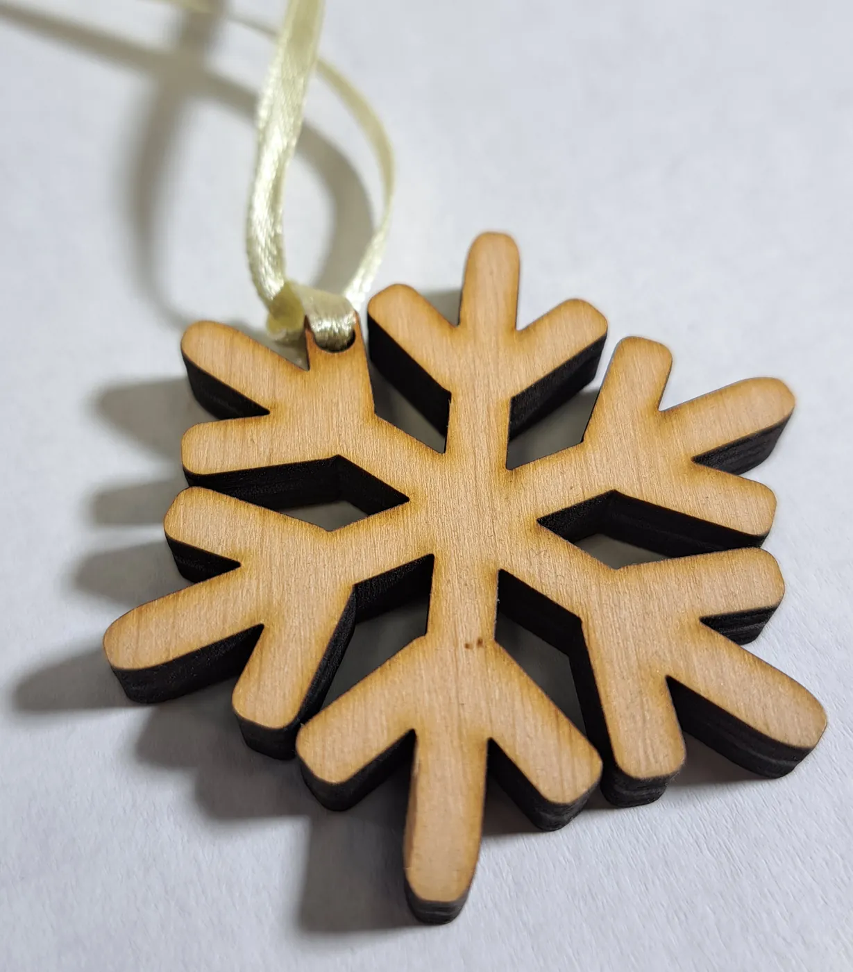 Plywood snowflake ornament hanging from a ribbon