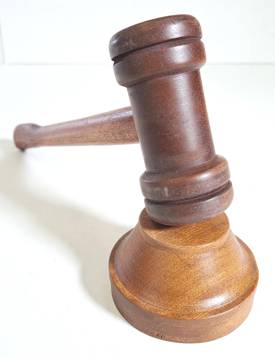 Turned wooden gavel resting on its round sound block