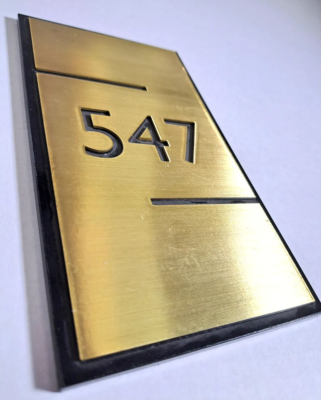 Room plate 547 with the numbers cut into a gold-tone face over a black backing
