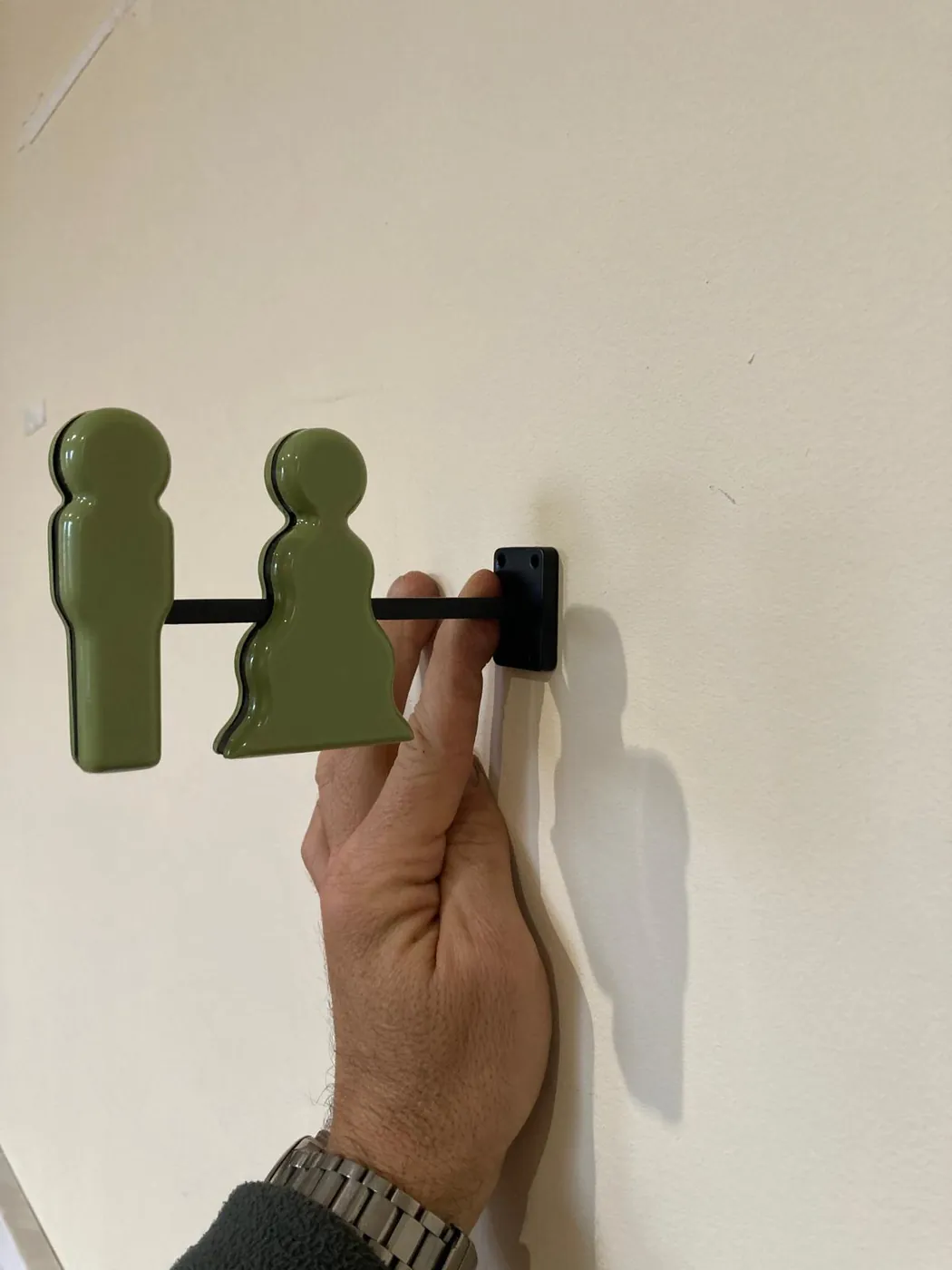 Green man and woman pictograms on a black projecting bracket, held against a wall