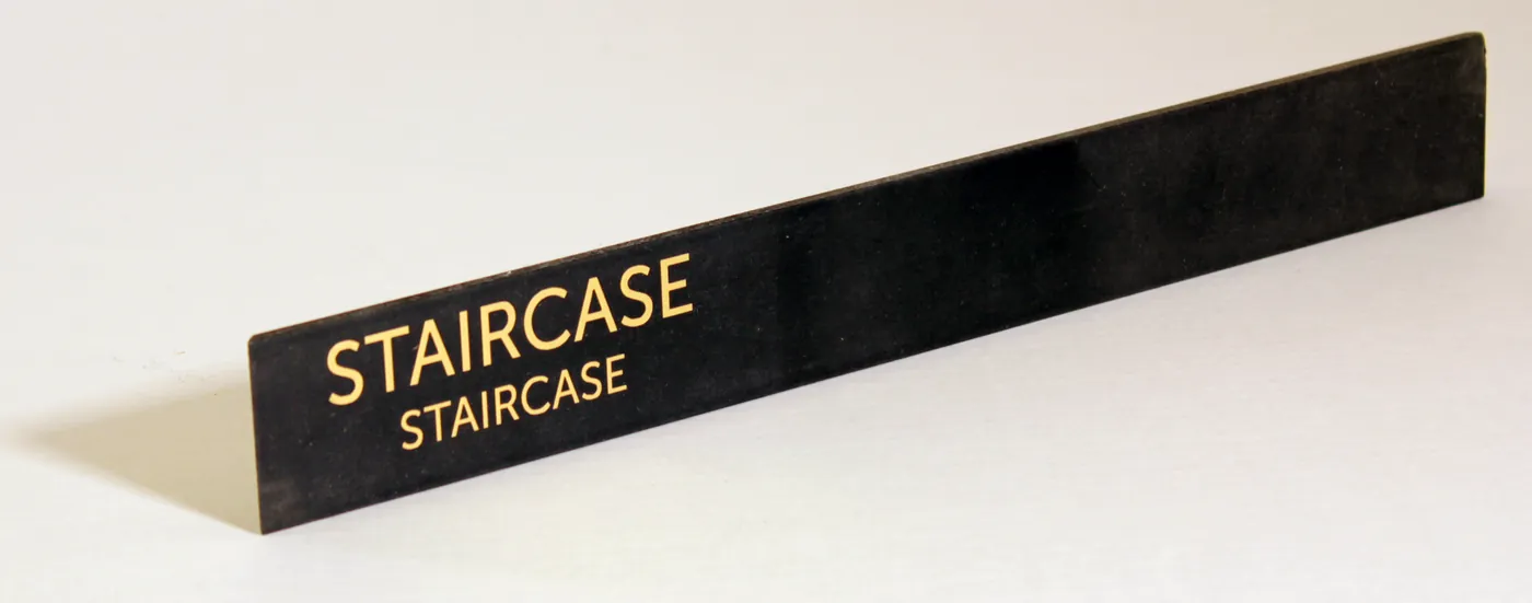 Long black sign with the word Staircase twice in gold-tone lettering
