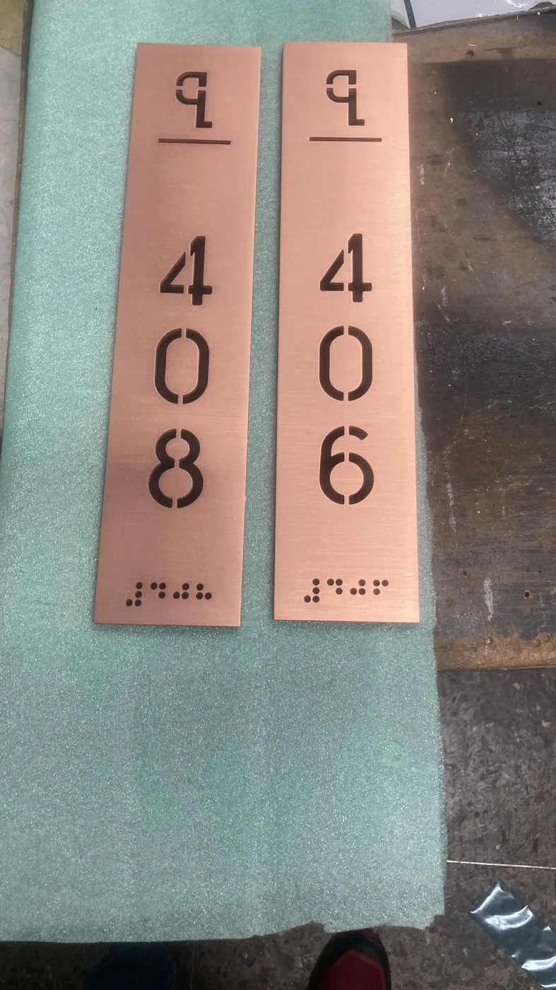 Two copper-tone room plates, 408 and 406, with raised tactile dots under the numbers
