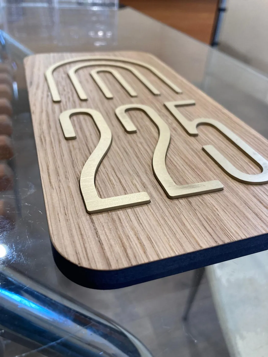 Room number 225 in gold-tone numerals under an arch motif, on a rounded wood-veneer plate