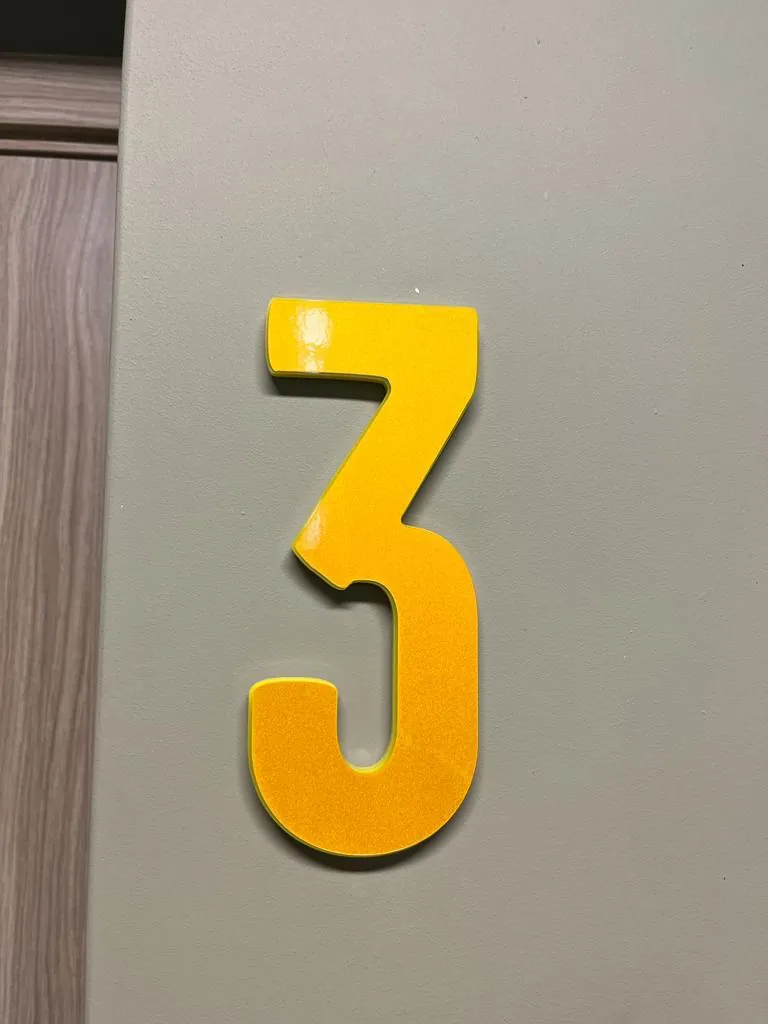 Single yellow numeral 3 fixed to a grey door