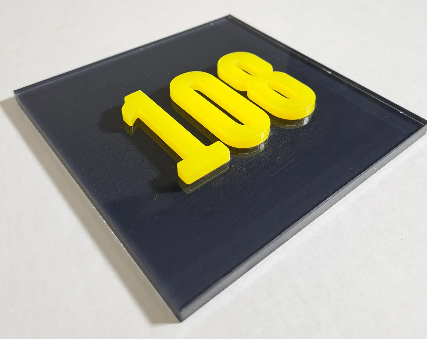 Raised yellow numerals 108 on a dark grey plate