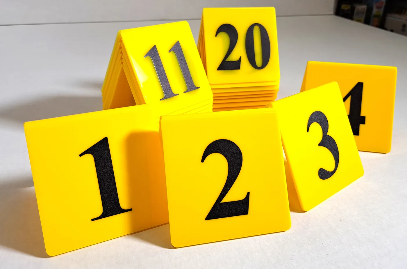Yellow folded table numbers, from 1 to 20, standing on a white table
