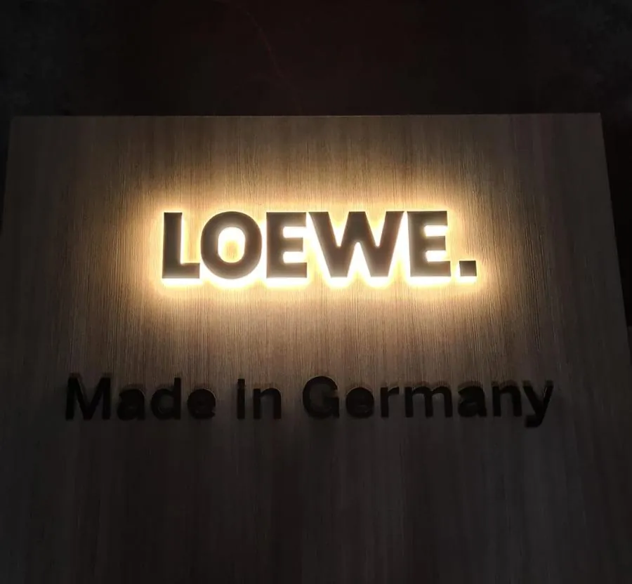 Backlit logo and a line of dark lettering on a wood-grain panel