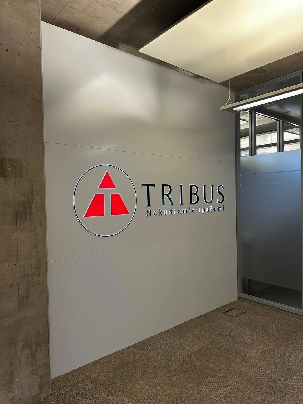 Round red and grey logo with the company name on a white reception wall
