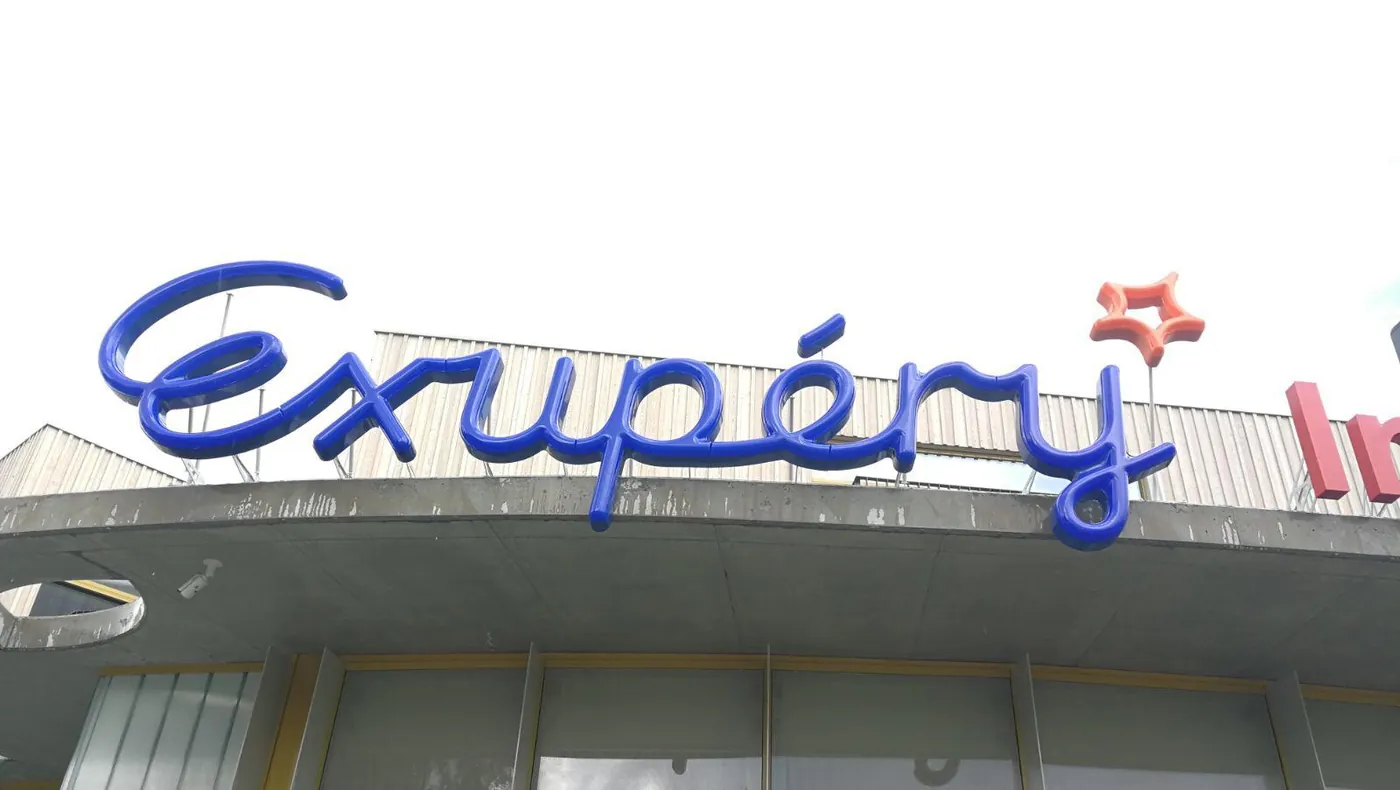 Blue script letters and a red star mounted on the canopy of a building