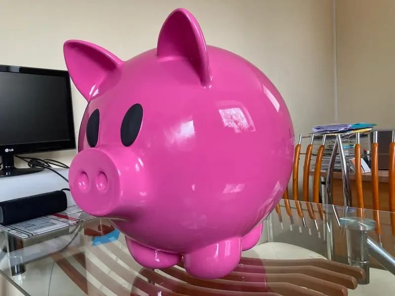 Large glossy pink pig figure with black eyes, standing on a glass table