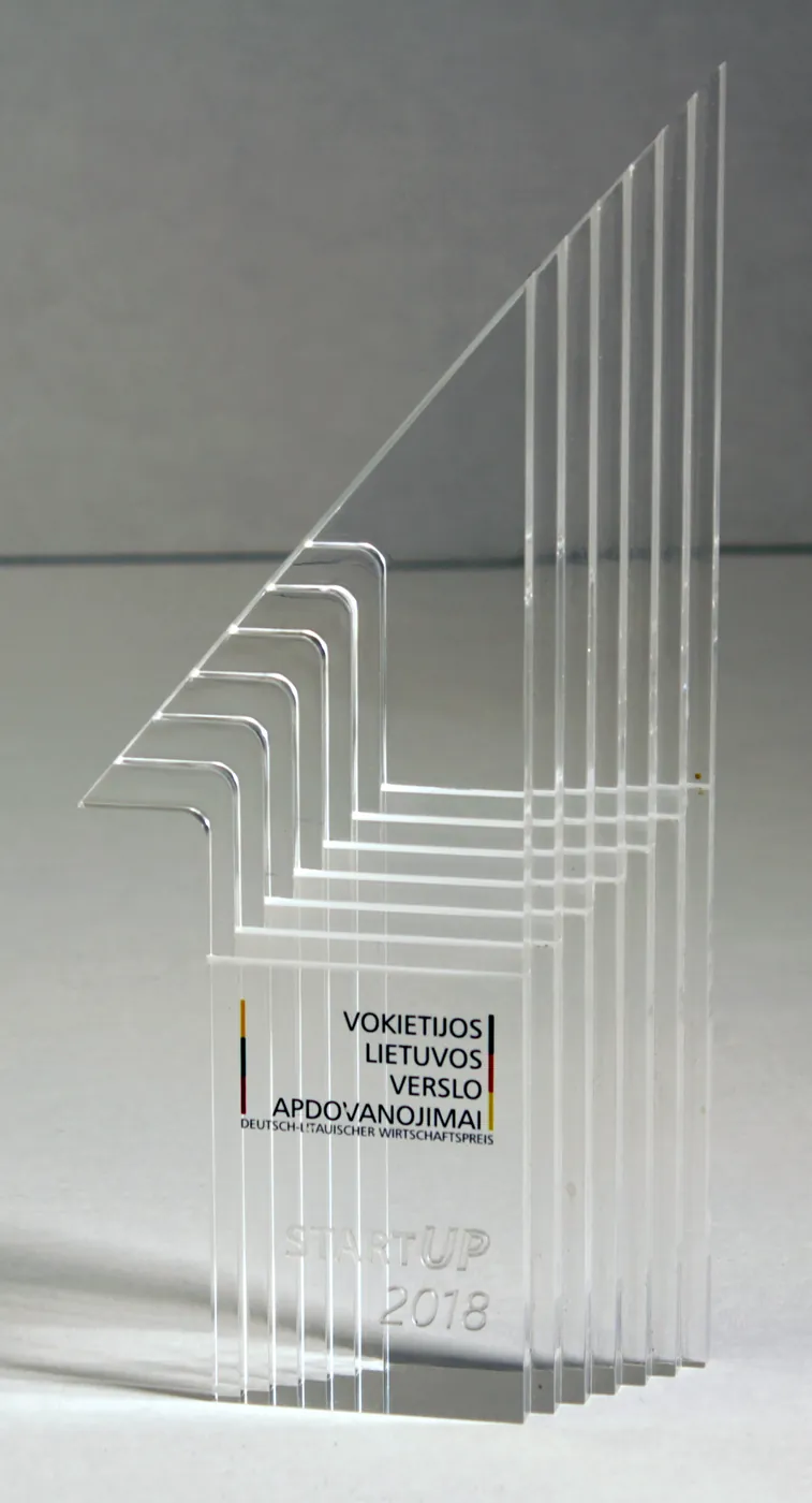 Business award made of clear acrylic sheets layered into a stepped shape, with printed text