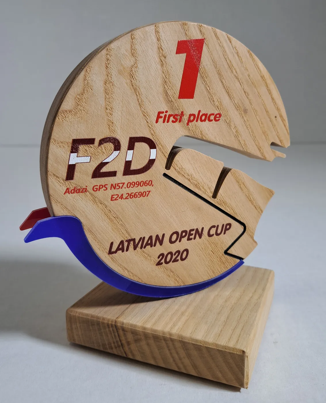 Wooden first-place trophy shaped like a disc with a cut-out track and a blue acrylic wave, on a wooden base